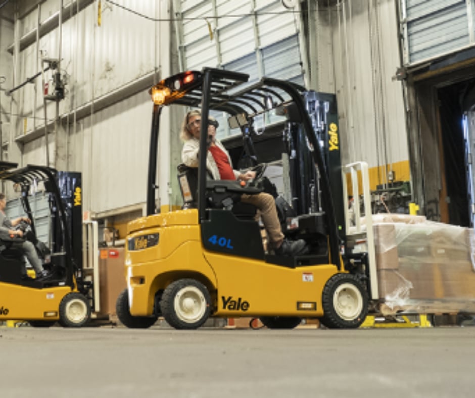 A LEVY operator on a yellow forklift unloading palletised freight at the warehouse loading dock.